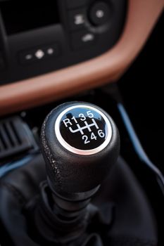 Detailed view of a manual gear shift knob in a car interior showcasing gear positions.