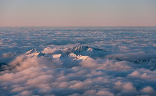 Free Stunning aerial view of snow-capped mountain peaks emerging through a sea of fluffy clouds. Stock Photo