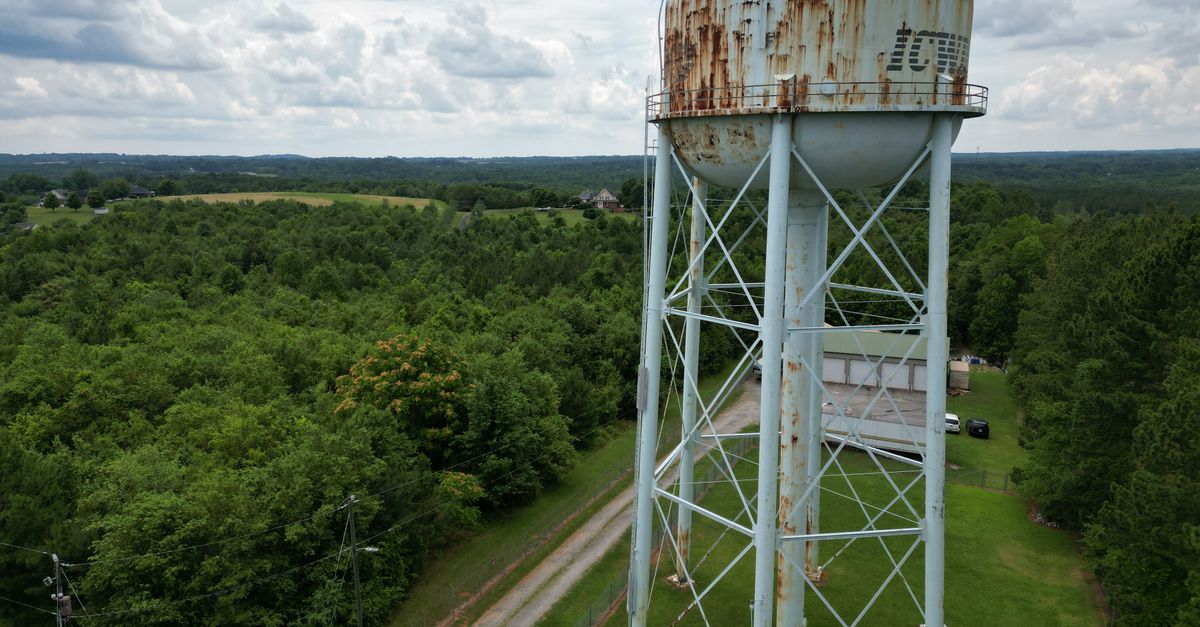 Drone shot of a rusted water tower amidst green fields in Campobello, SC.