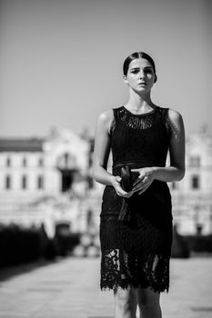 Black and white portrait of a fashionable woman outdoors in an urban setting.