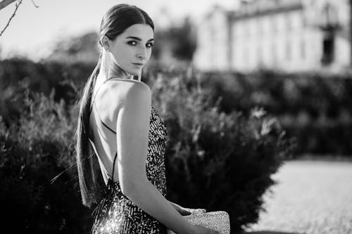 Grayscale Photography of a Beautiful Woman in Elegant Backless Dress Looking at the Camera