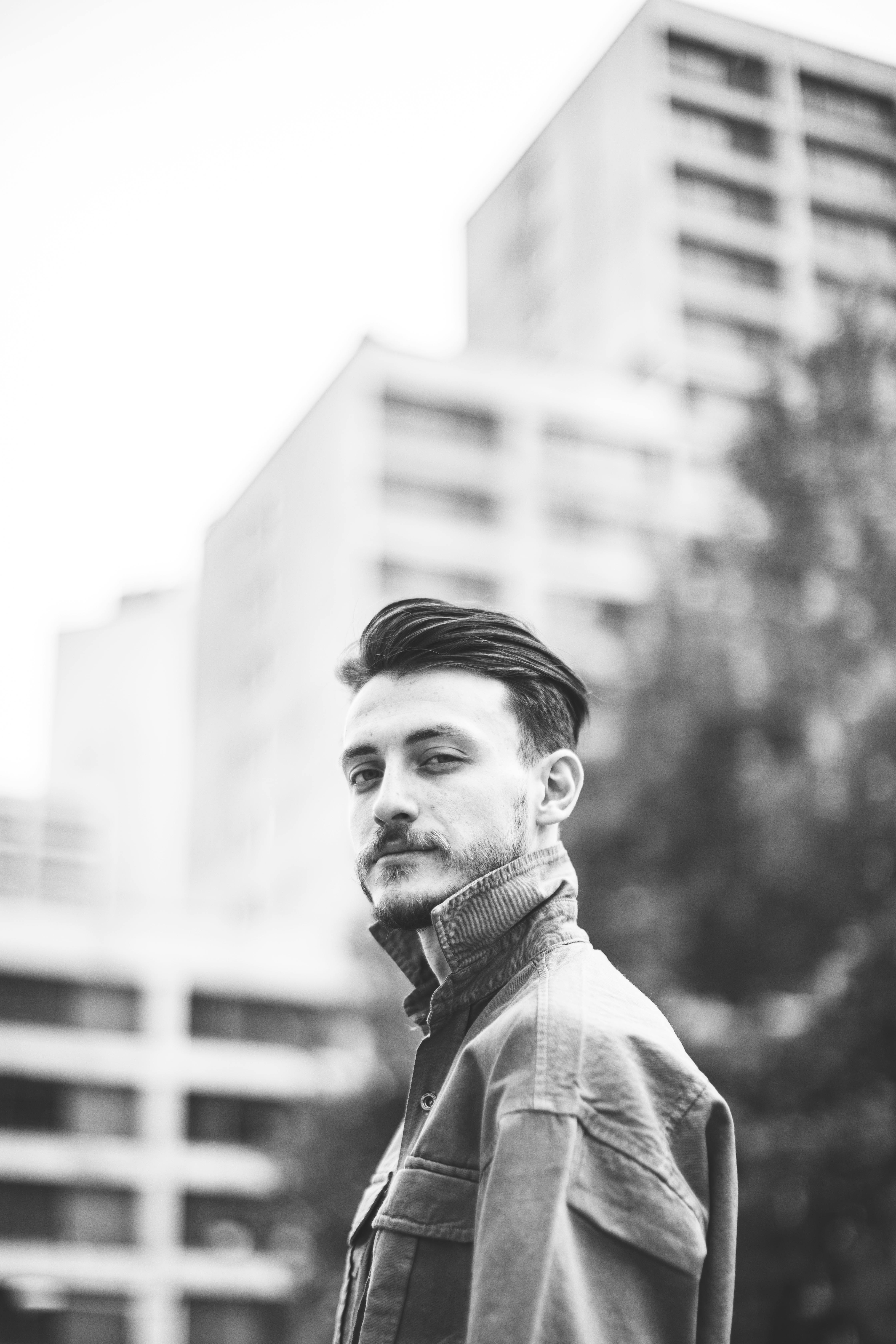 Black and white portrait of a man in urban Iran featuring high-rise buildings.