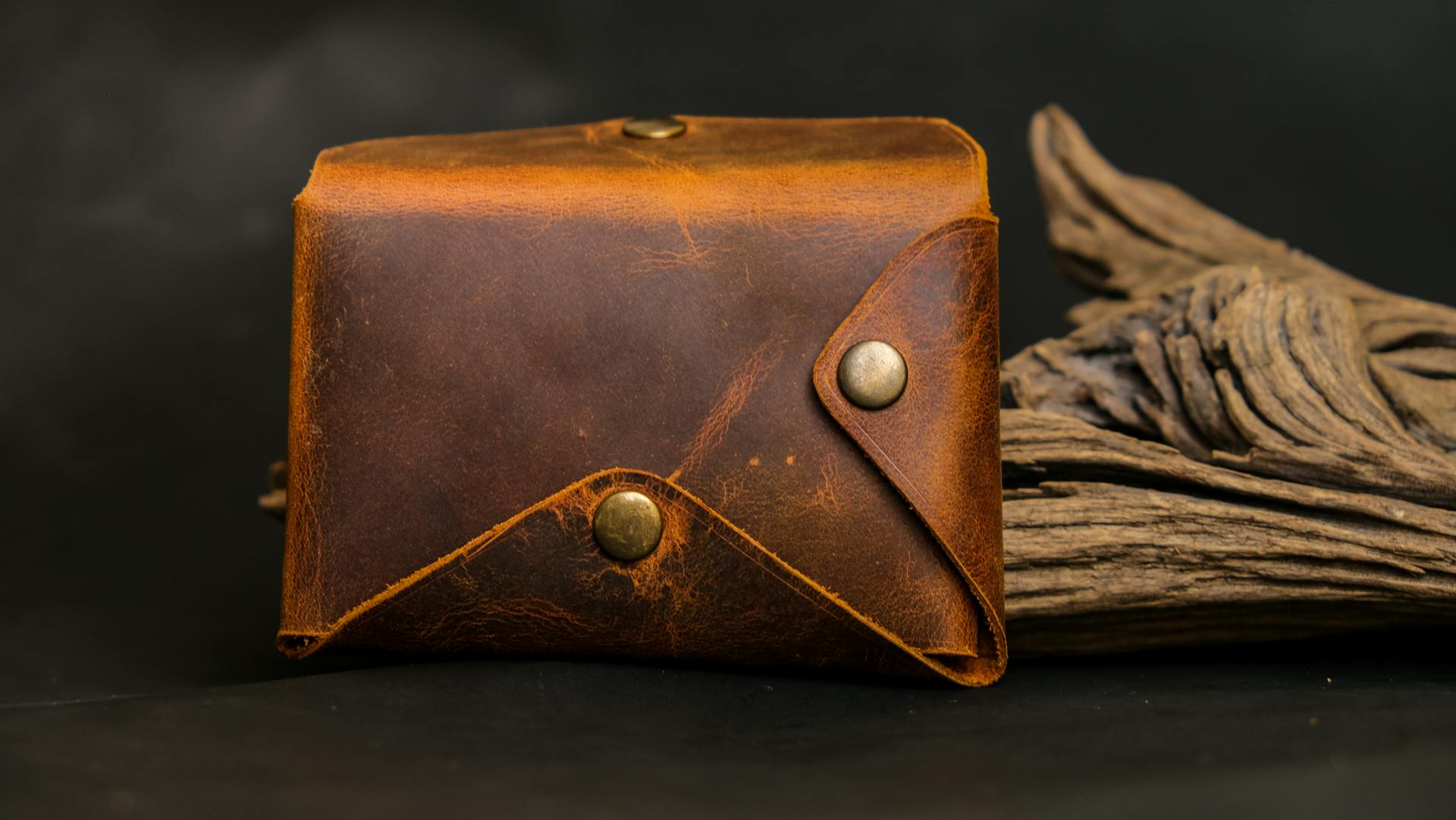 Close-up of a rustic leather wallet against a dark wood background.