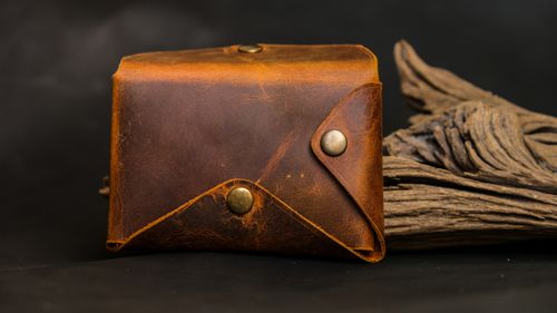Free Close-up of a rustic leather wallet against a dark wood background. Stock Photo