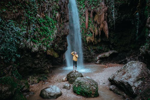 Man Standing on the Rock near Waterfall