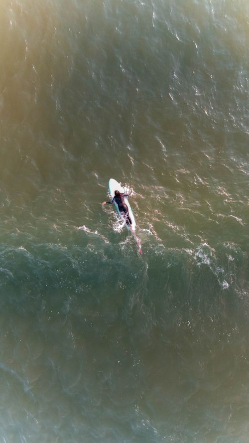 Free Top view of a surfer paddling through ocean waves in Florianópolis, Brazil. Stock Photo