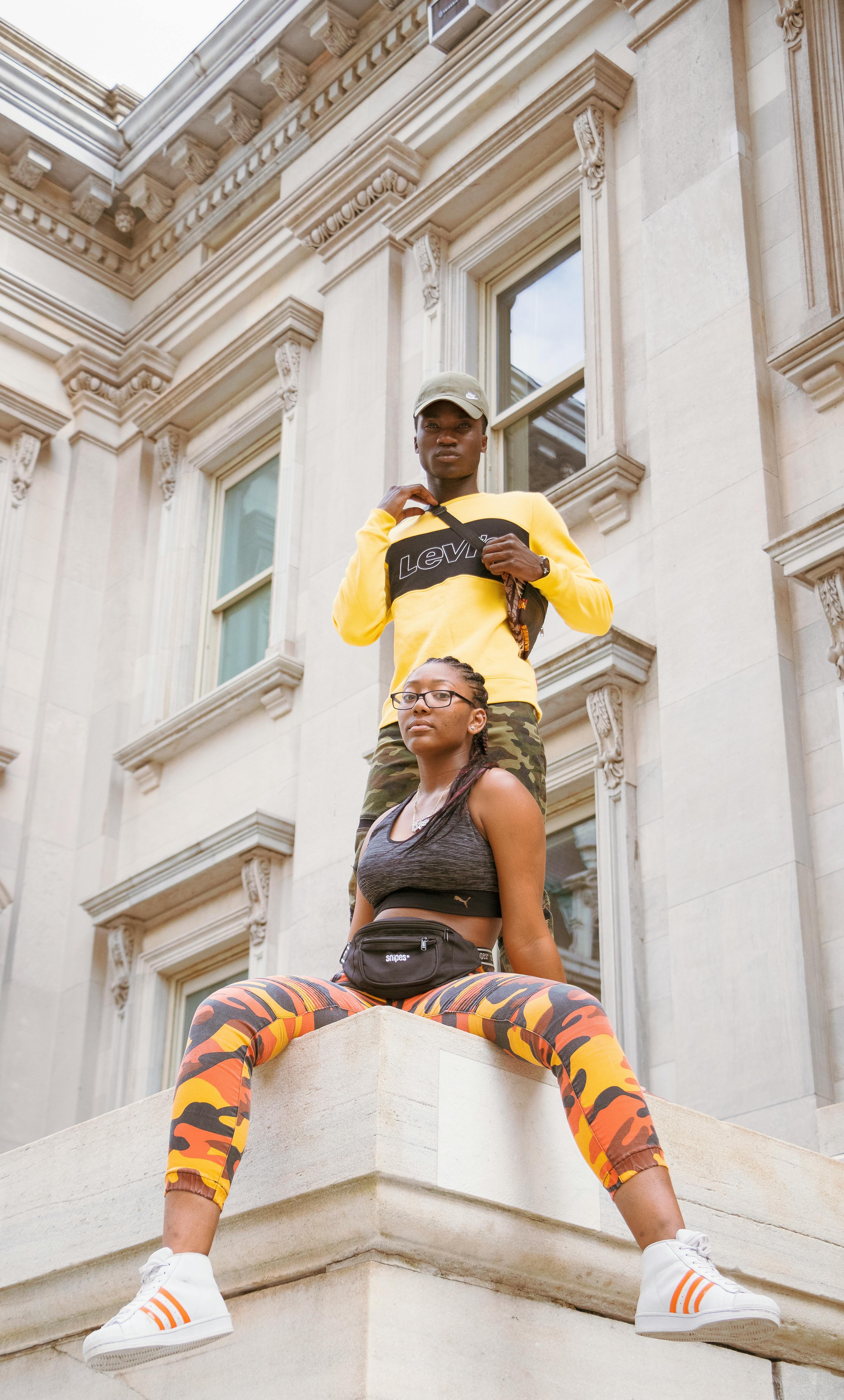 Stylish young adults posing confidently on an urban building, showcasing streetwear fashion.