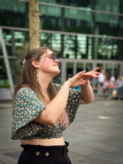 Free A cheerful young woman enjoying a dance in an urban outdoor setting on a sunny day. Stock Photo
