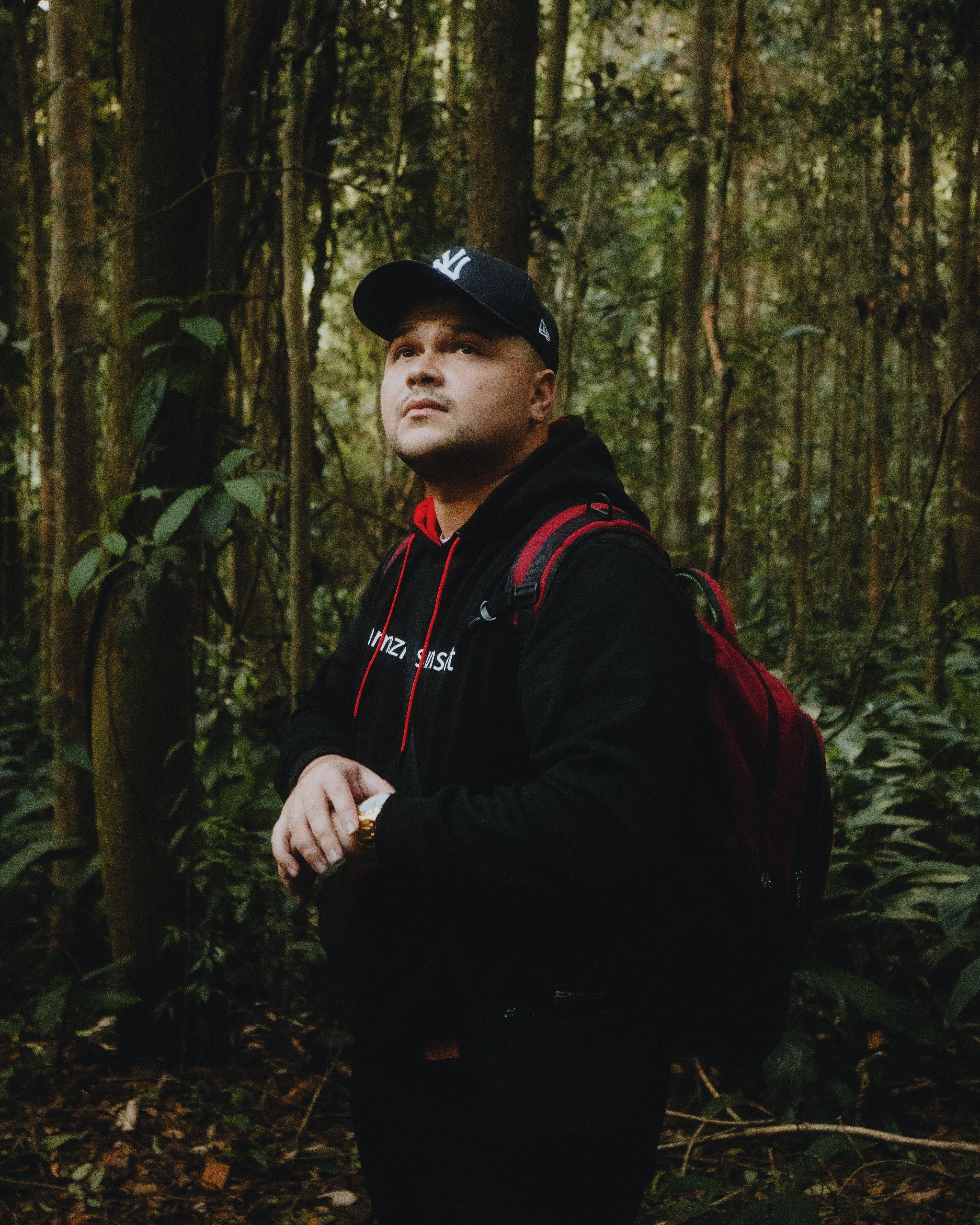 Adult male with a backpack exploring a dense forest during daytime, showcasing adventure and nature.