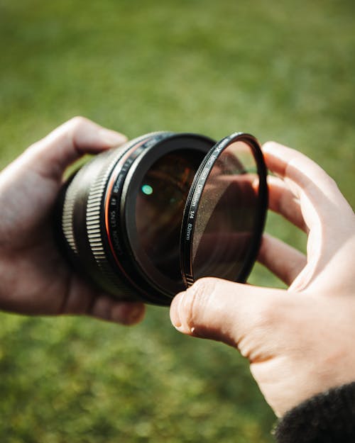Close-Up Shot of a Person Holding a Camera Lens