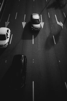 Aerial shot of cars on an urban street in black and white, emphasizing city life and motion.
