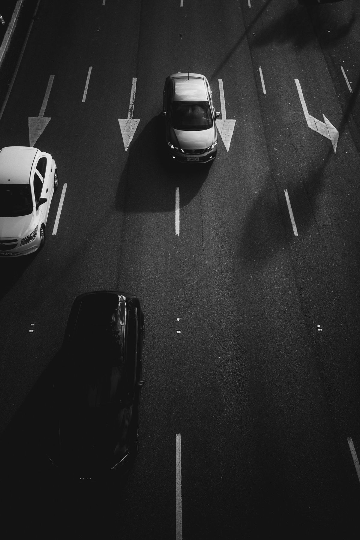 Black-and-white overhead view of cars on a multi-lane road