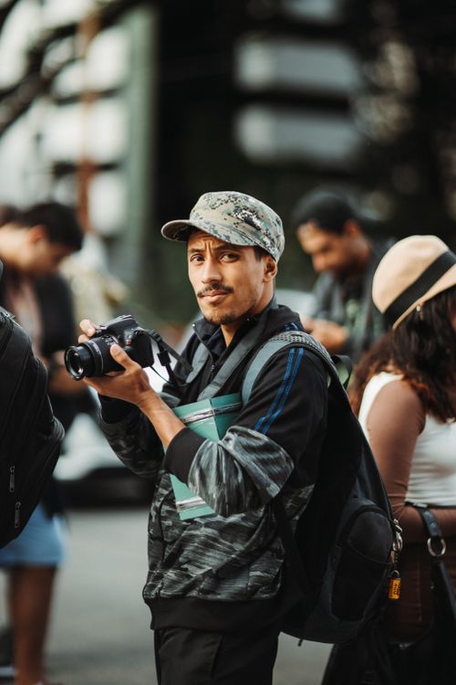 Free Man holding a camera in an urban environment with a shallow depth of field. Stock Photo