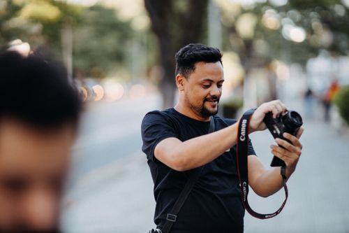 Free Man taking a photo on a street with a DSLR camera, embodying the art of photography. Stock Photo