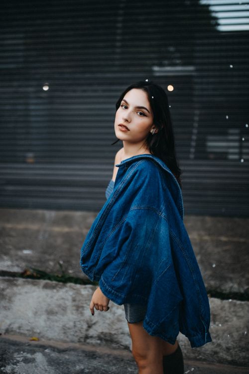 Free Fashionable young woman posing with denim jacket in an urban setting. Stock Photo
