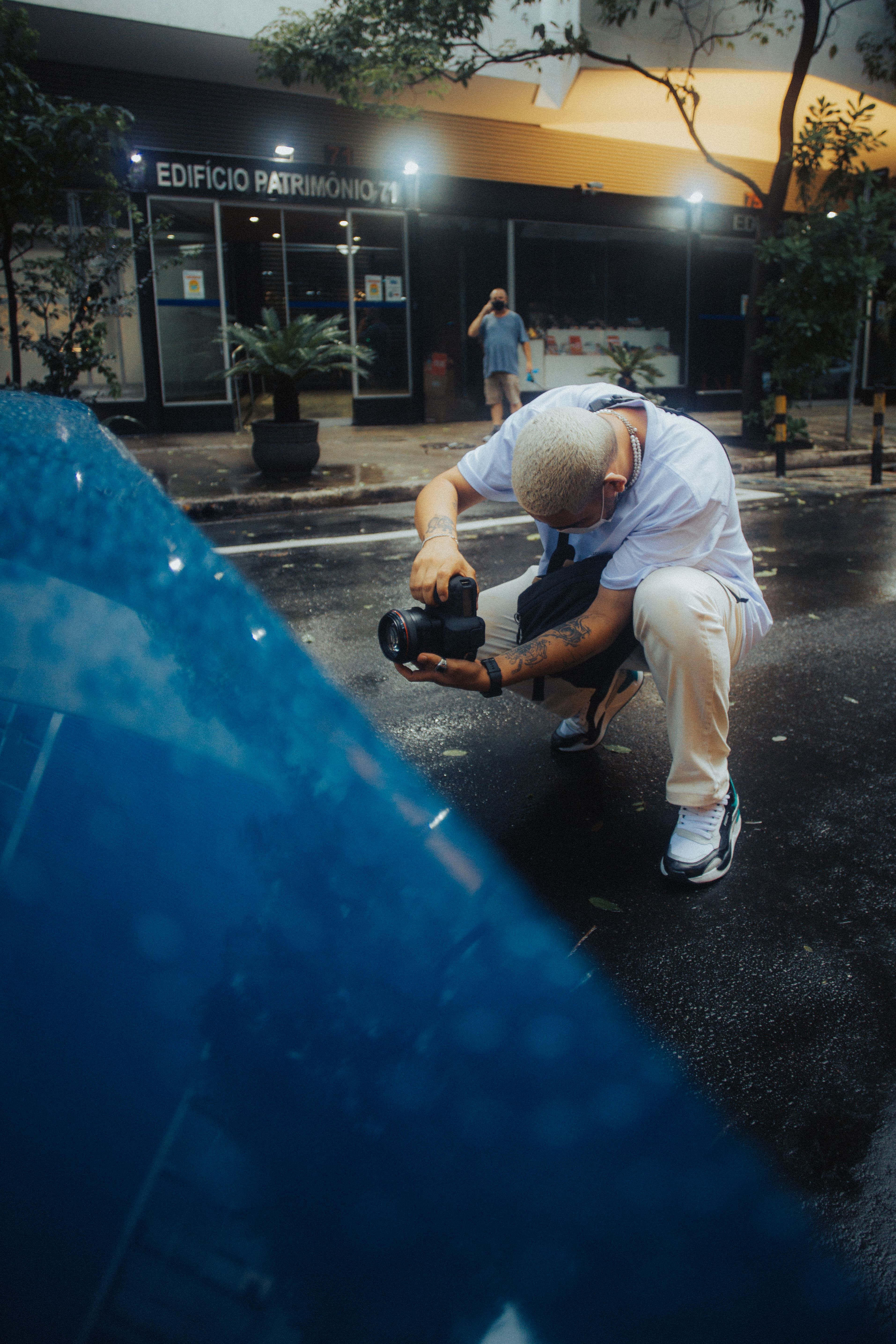Photographer crouching on a wet urban street taking pictures after rain.