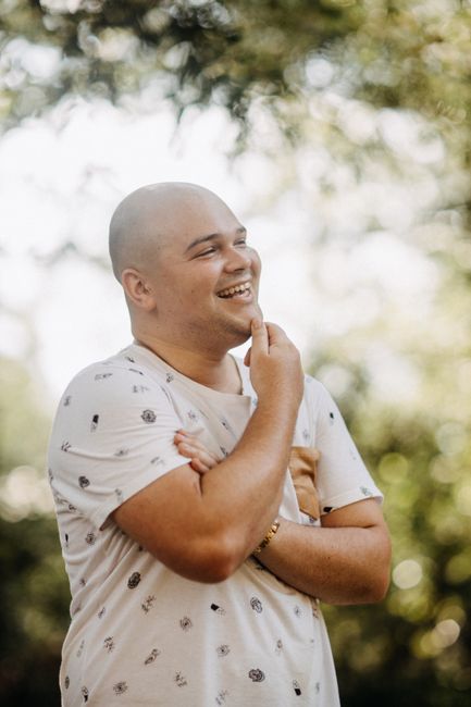 Fotomural Un hombre calvo sonriente con una camisa blanca casual disfrutando de un día soleado al aire libre.