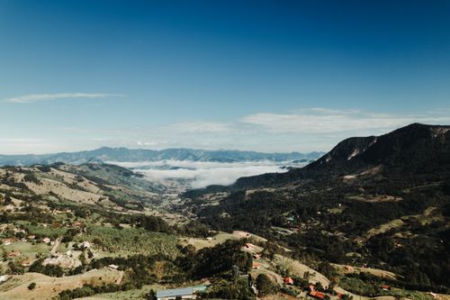 Free Beautiful aerial view of a mountainous valley beneath a clear blue sky, capturing the essence of nature's beauty. Stock Photo