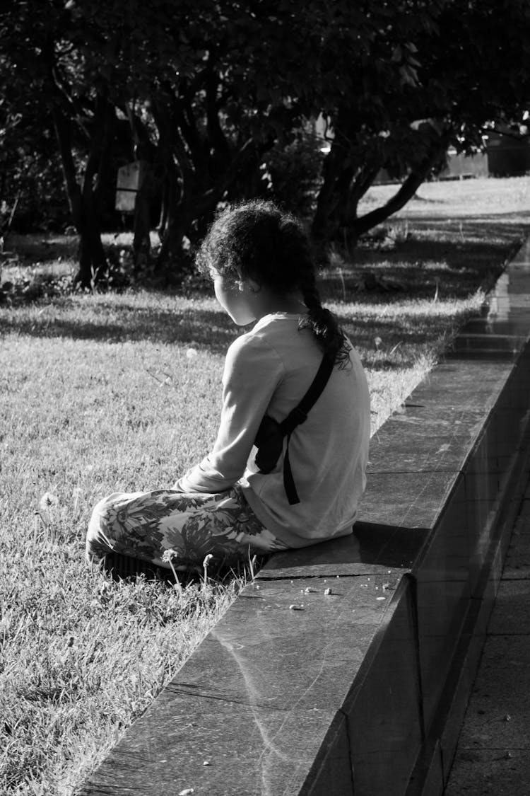 Little Girl Sitting On Grass In Park