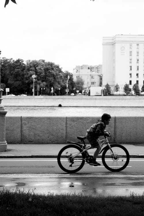 Grayscale Photo of a Kid Riding a Bicycle