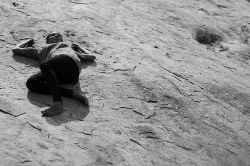 Free A child relaxes on a rocky surface, captured in black and white, evoking a sense of peace. Stock Photo