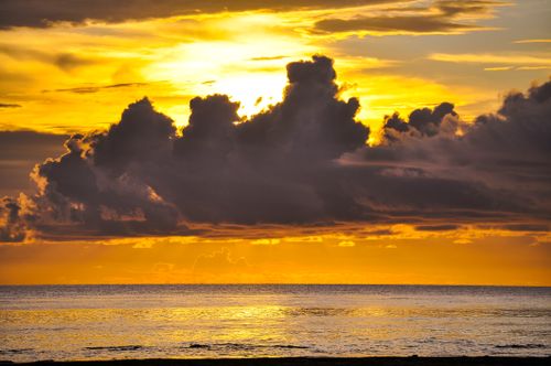 Free Stunning ocean sunset with dramatic clouds and vibrant colors reflecting on the water. Stock Photo
