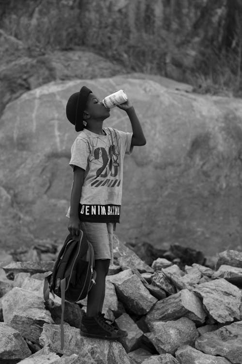 Free Young Boy Standing on Rocks and Drinking Stock Photo