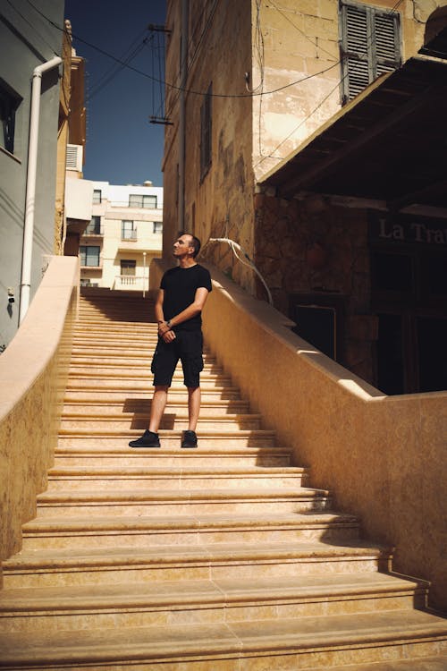 A Man in Black Shirt Standing on Concrete Stairs