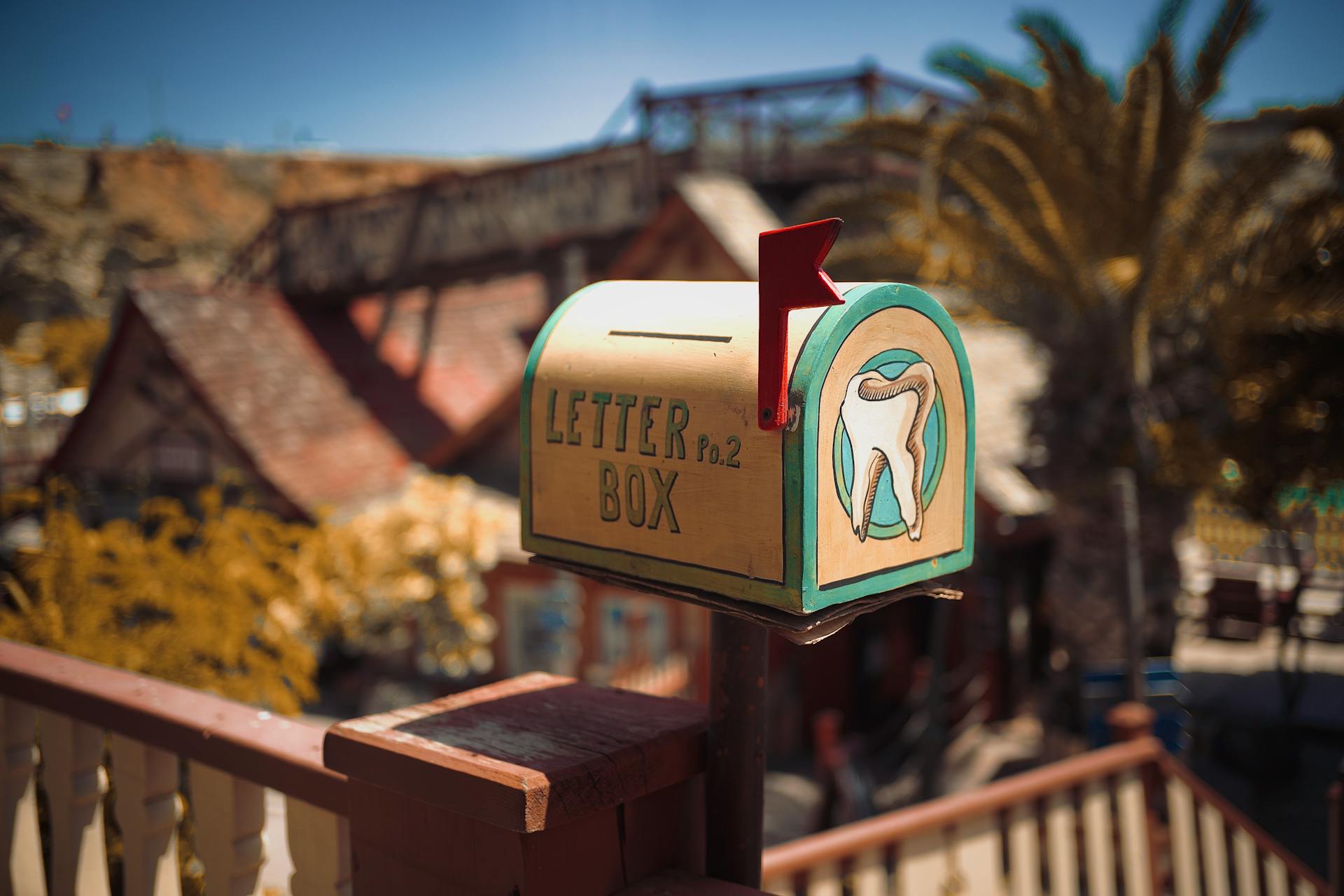 A vintage mailbox with dental artwork in a sunny outdoor setting.