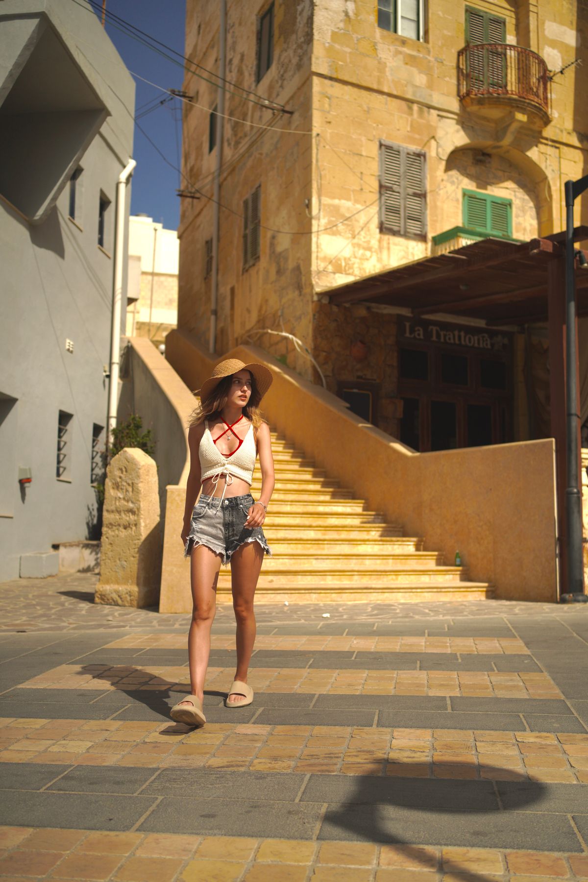 A woman in a white crop top walking on the street in denim shorts — chic summer street style