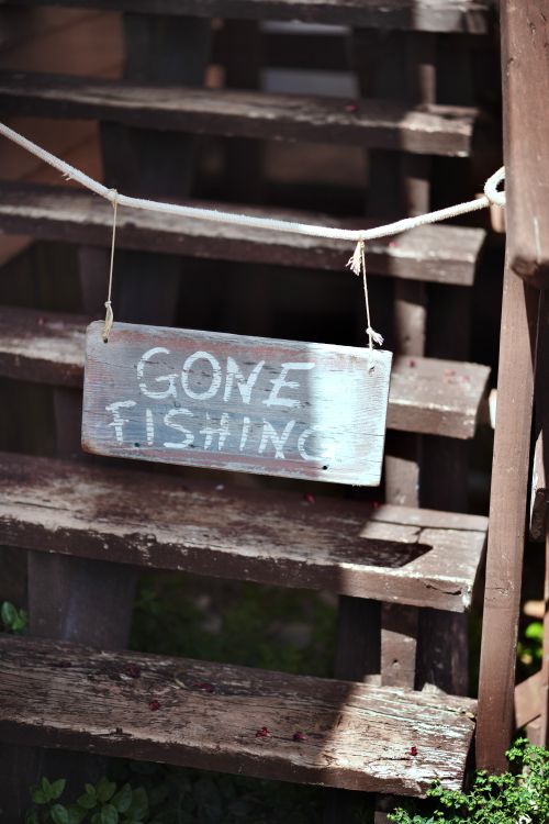 Free A charming 'Gone Fishing' sign hangs on rustic wooden steps, capturing a laid-back ambiance. Stock Photo