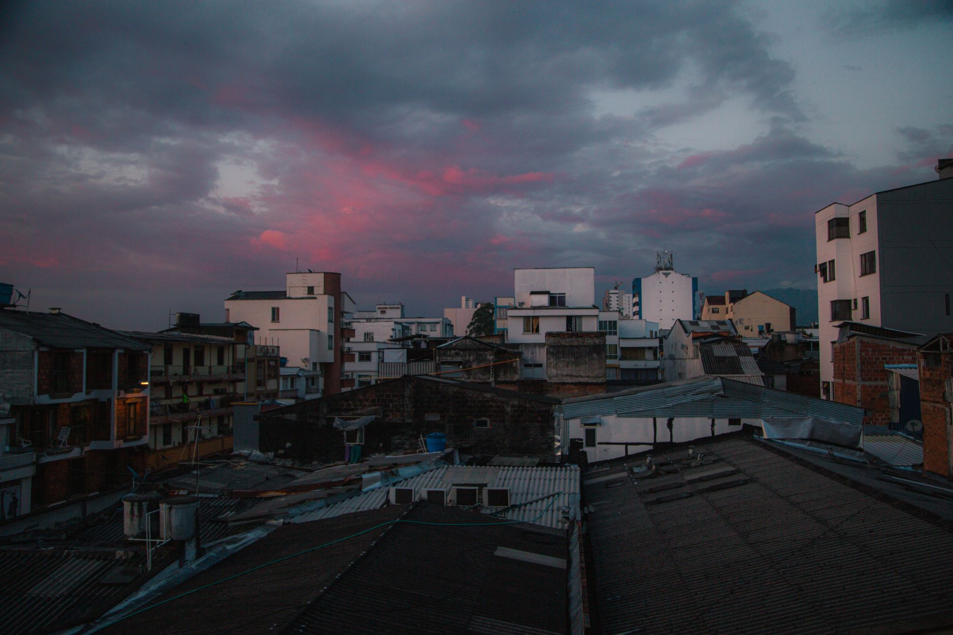 Twilight urban skyline with a cloudy pink sunset and diverse rooftops.