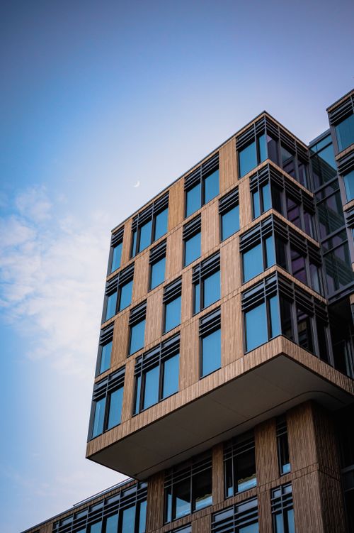 Free Contemporary architecture with glass panels and wooden accents on a bright day. Stock Photo