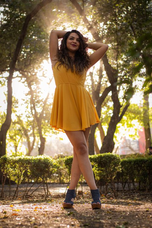 Free Woman in yellow dress smiles while posing in a sunlit park Stock Photo
