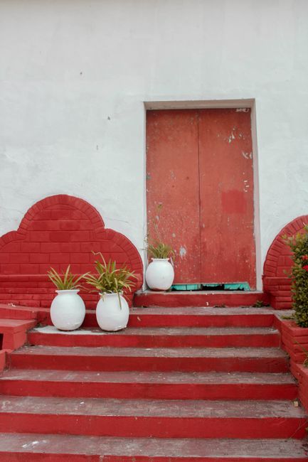 Vibrant red and white doorway with potted plants in Tapijulapa, Mexico.