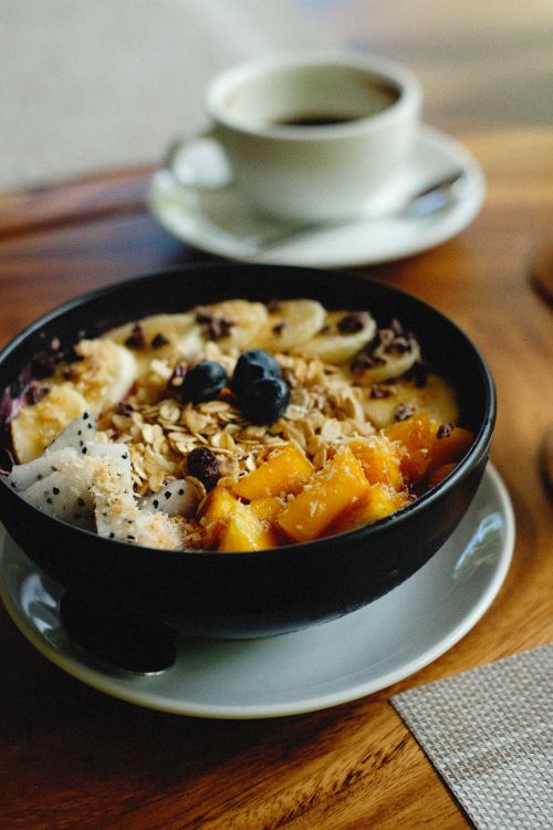 Free A delicious fruit and granola bowl served in a cozy setting with a cup of coffee. Stock Photo
