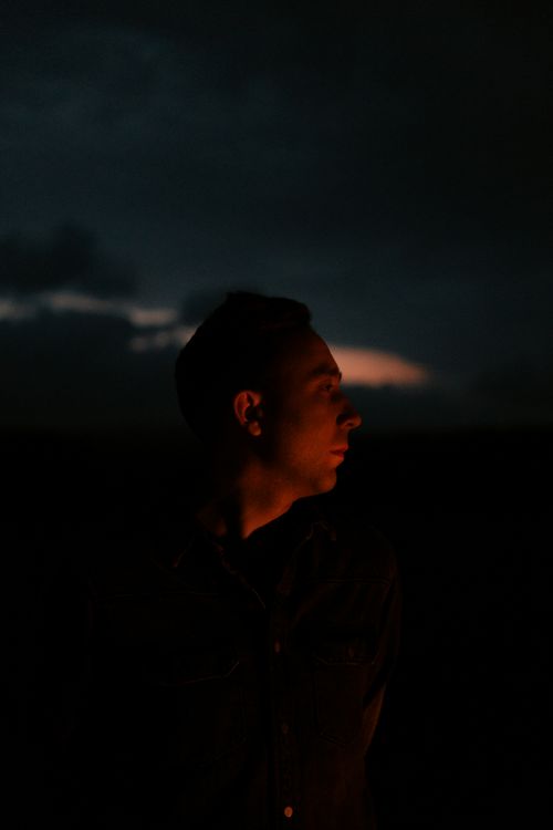 Free Silhouette of a man looking afar against a dark, moody night sky. Stock Photo