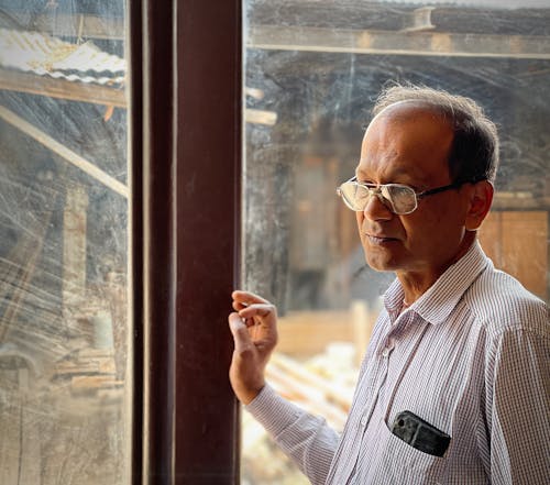 A Man Standing Beside the Glass Window