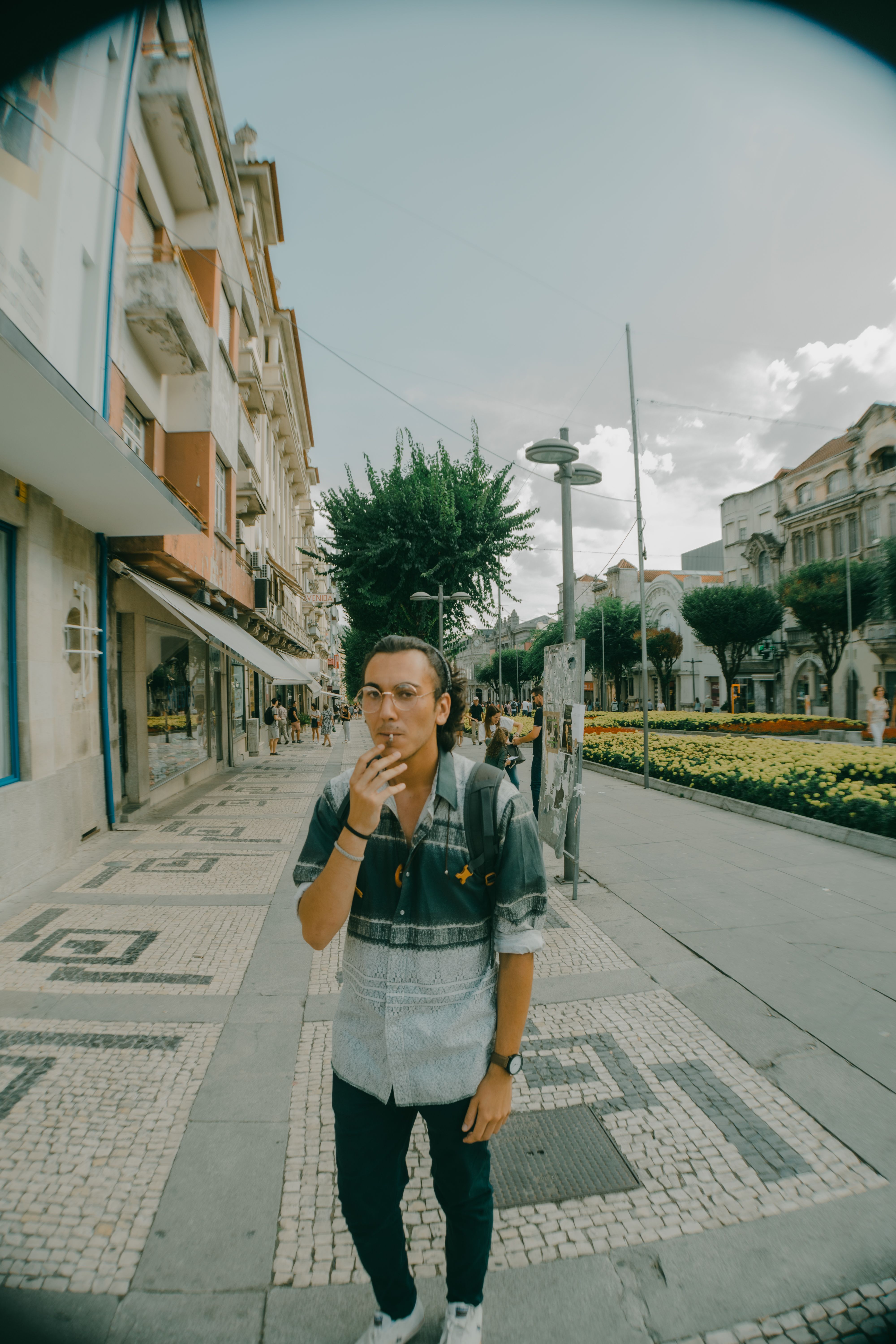 A young man smokes while strolling through a vibrant urban street.