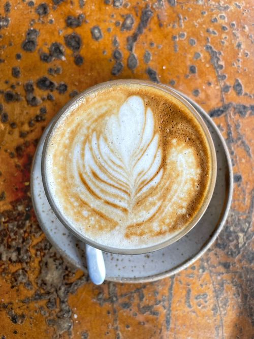 Free A captivating top view of a latte with artistic foam on a rustic table, perfect for coffee enthusiasts. Stock Photo