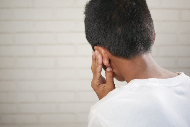 Back View Of A Boy Covering His Ear