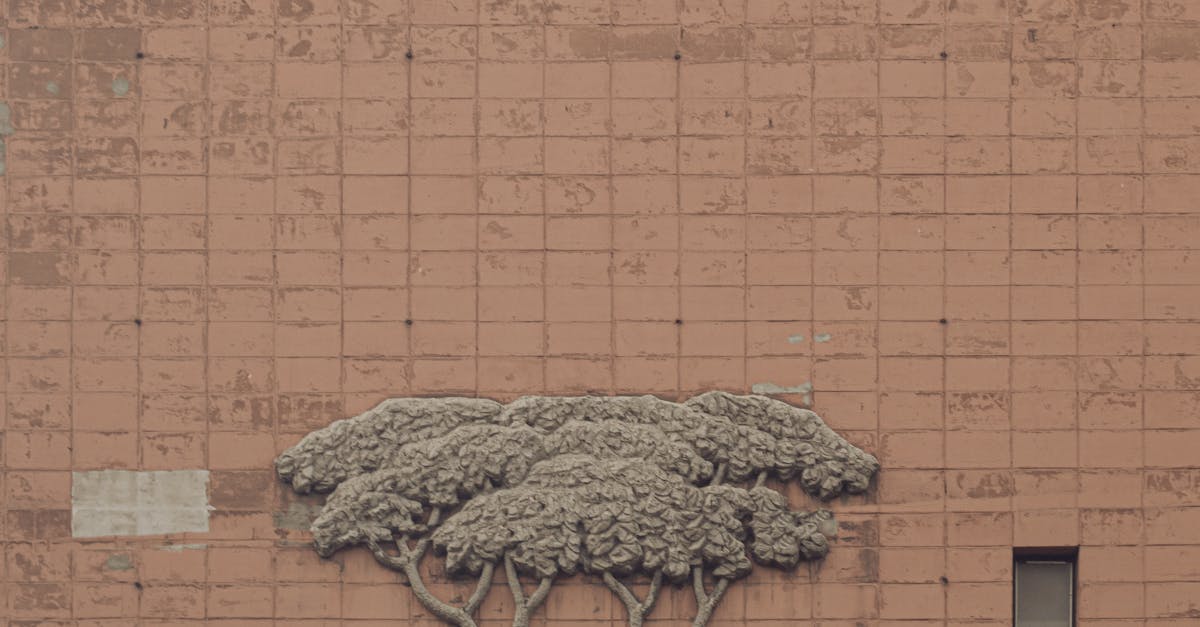Stone sculpture relief depicting people dancing around a tree on a brick wall.