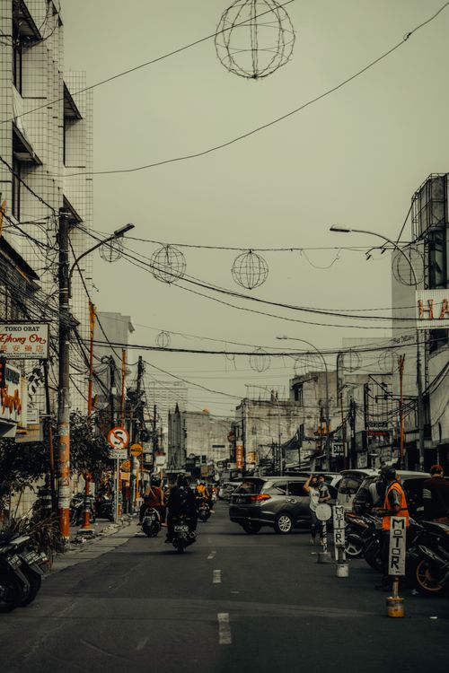 Free Busy city street with cars, motorcycles, and people navigating through fog and urban surroundings. Stock Photo