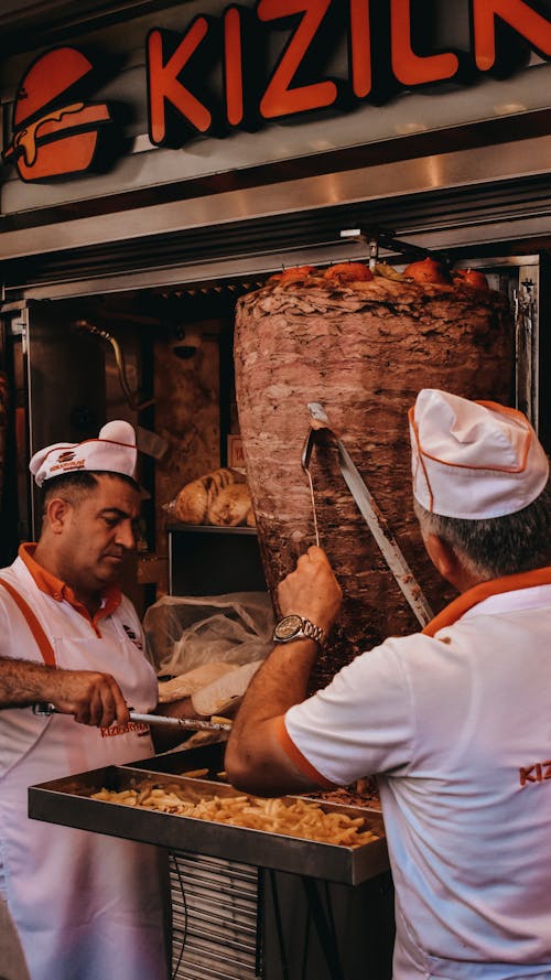 A Person in White Uniform Scraping Meat with a Long Knife