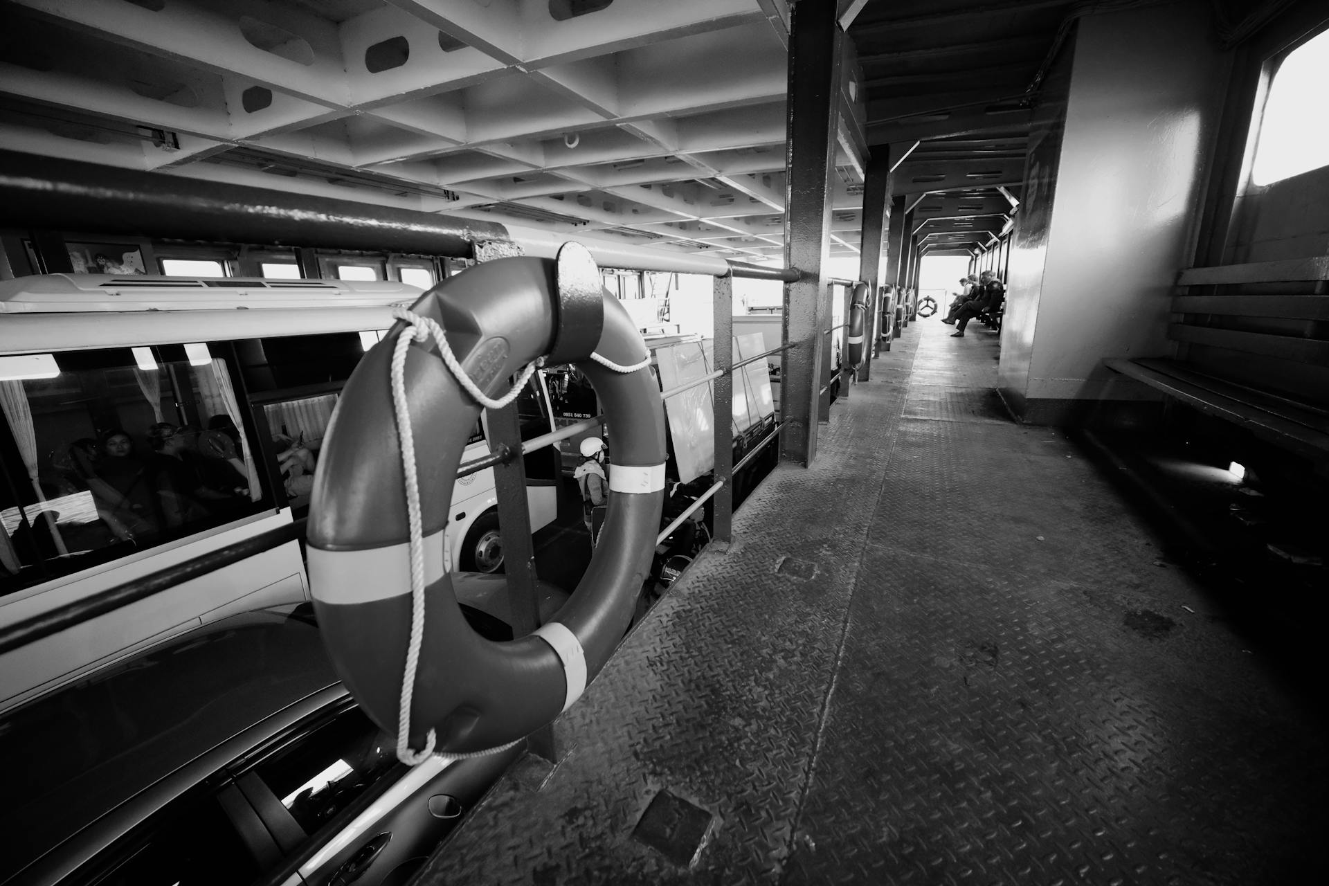 Black and white photo of a ferry interior transporting vehicles across water.