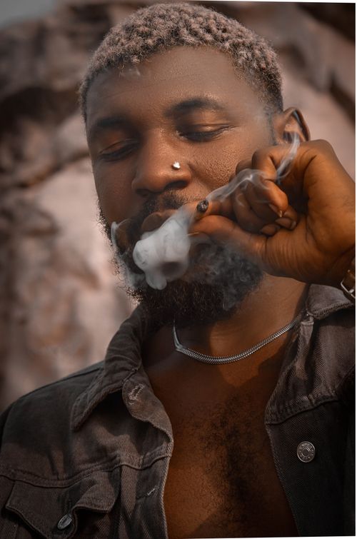 Free Close-up portrait of an African man smoking outside, exuding a relaxed vibe. Stock Photo