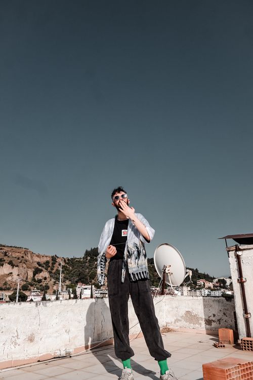 Free Stylish man in urban setting on rooftop under a clear blue sky, embodying modern fashion. Stock Photo