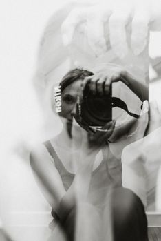 Artistic double exposure of a woman with a camera, blending reflection and portrait photography.