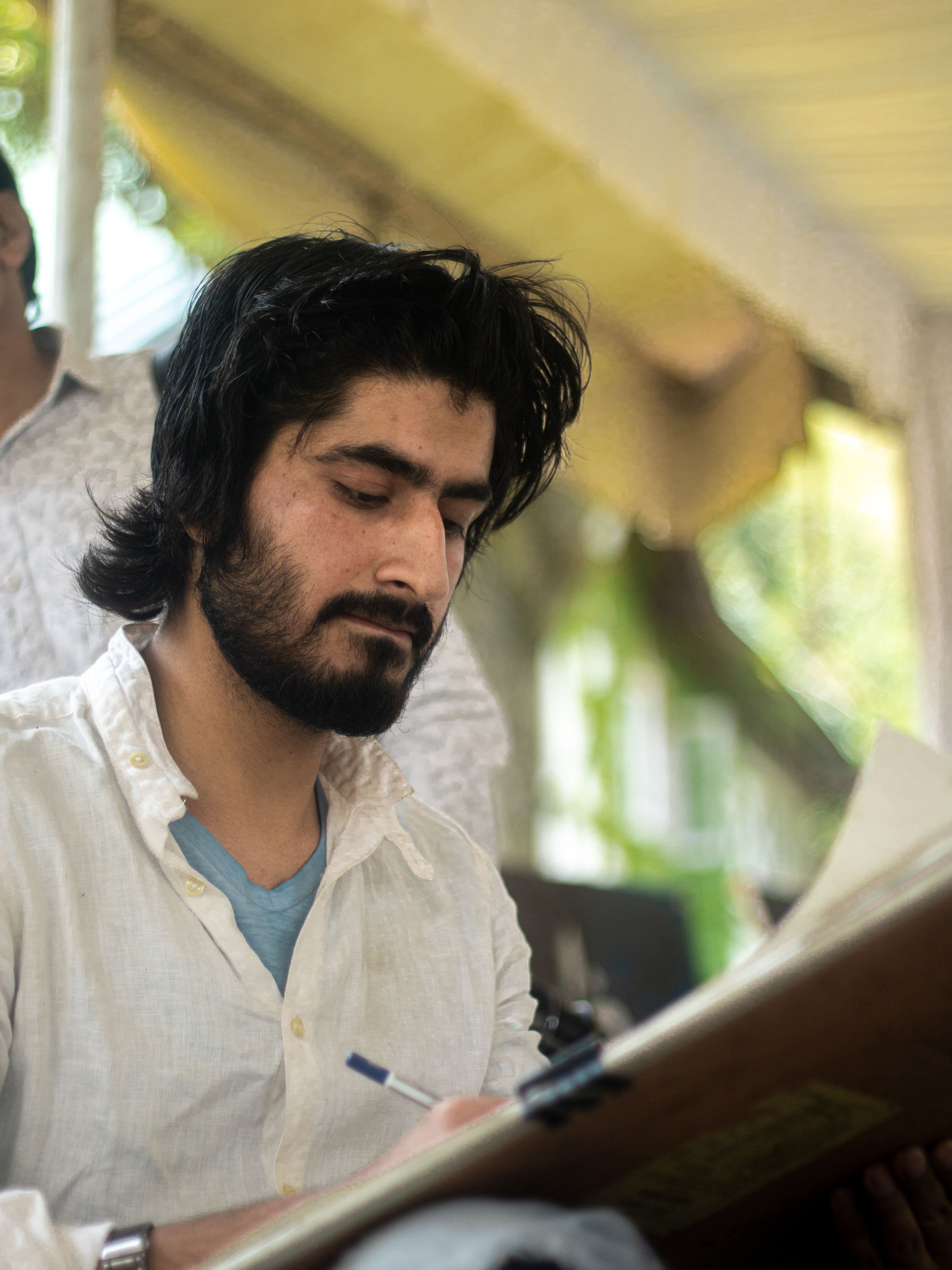 Young South Asian artist sketching outdoors in Srinagar, capturing creativity in motion.