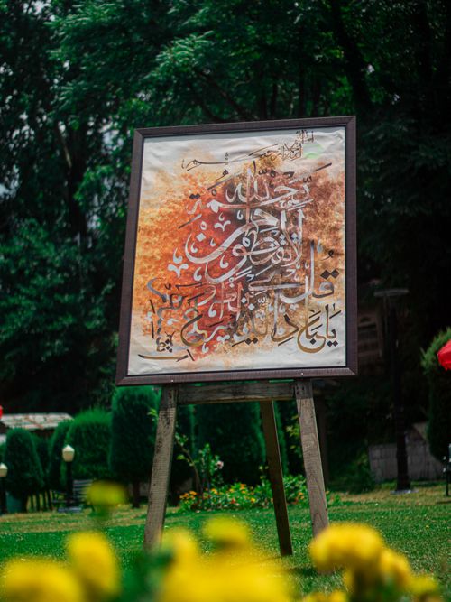Free A beautiful framed calligraphy art piece displayed outdoors in an enchanting Srinagar garden. Stock Photo